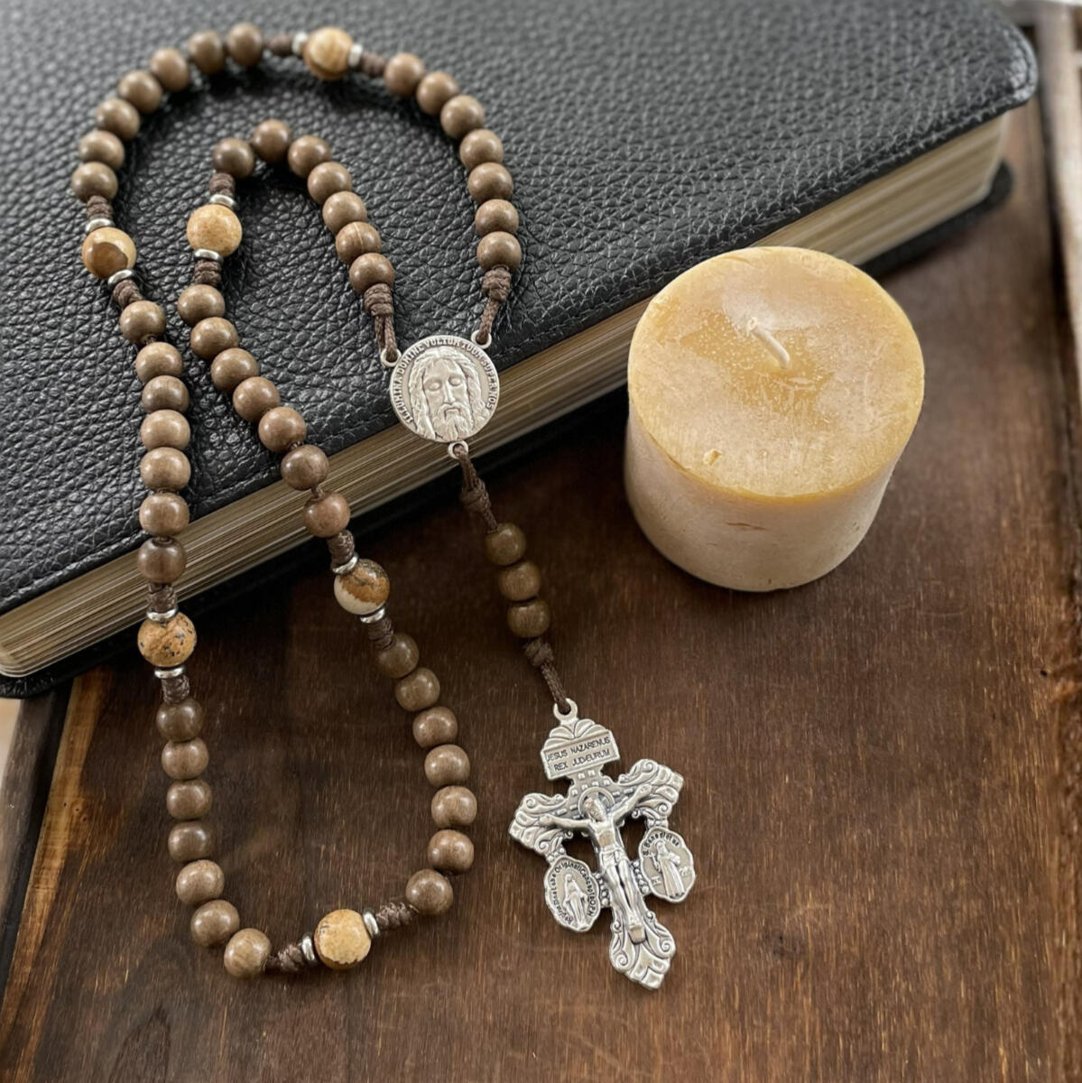 A handmade Seven Sorrows Rosary made from paracord with a silver Pardon Crucifix and silver Holy Face of Jesus centerpiece and the Hail Mary beads are grey brown wood and the Our Father beads are brown stone.