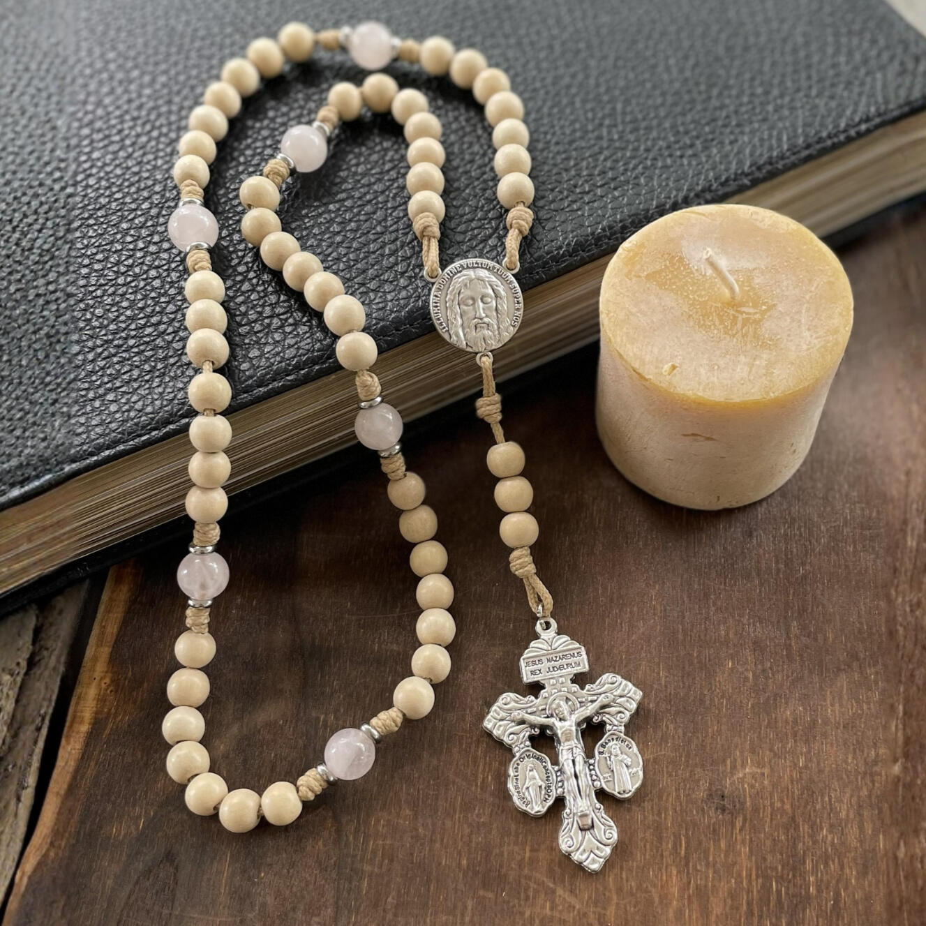 A handmade Seven Sorrows Rosary made from paracord with a silver Pardon Crucifix and silver Holy Face of Jesus centerpiece and the Hail Mary beads are cream color wood and the Our Father beads are white stone with hints of pink.