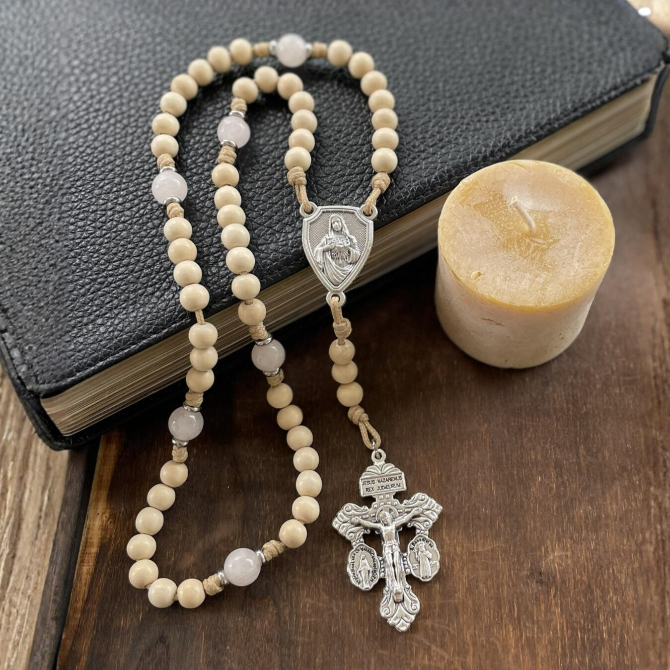 A handmade Seven Sorrows Rosary made from paracord with a silver Pardon Crucifix and silver Immaculate Heart of Mary centerpiece and the Hail Mary beads are cream color wood and the Our Father beads are white stone with hints of pink.
